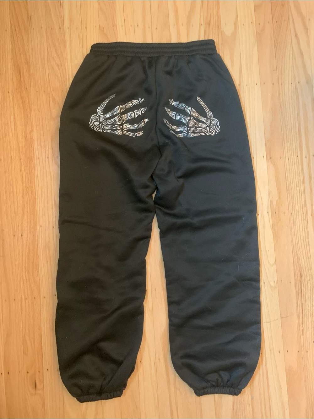 Black sweatpants with white skeleton hand graphics on the back